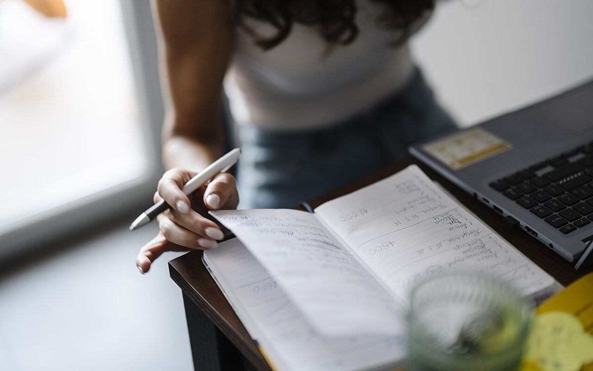 Person writing in a notebook while sitting at a desk