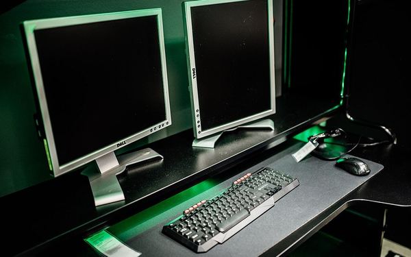 Dual monitor setup in a gaming room with keyboard and mouse in focus